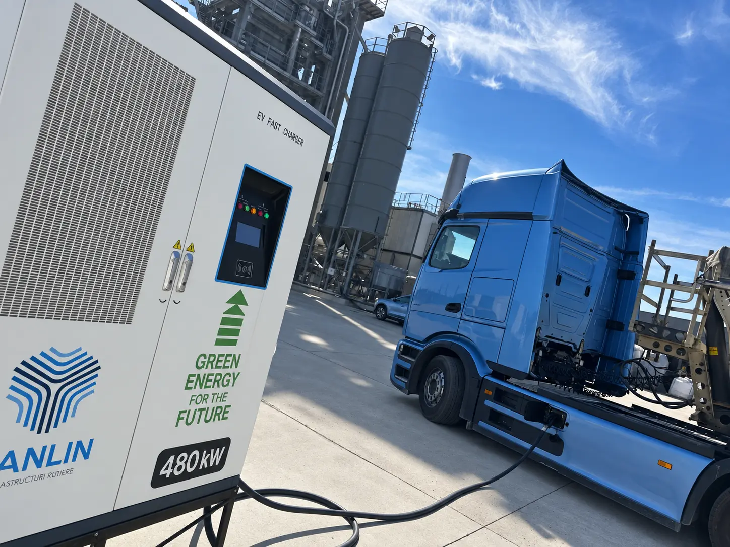 Stație DC de 480 kW cu grafică personalizată pentru client, într-un amplasament industrial cu camion.